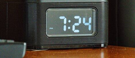 Un orologio digitale mostra le 19:24 su un altoparlante nero.