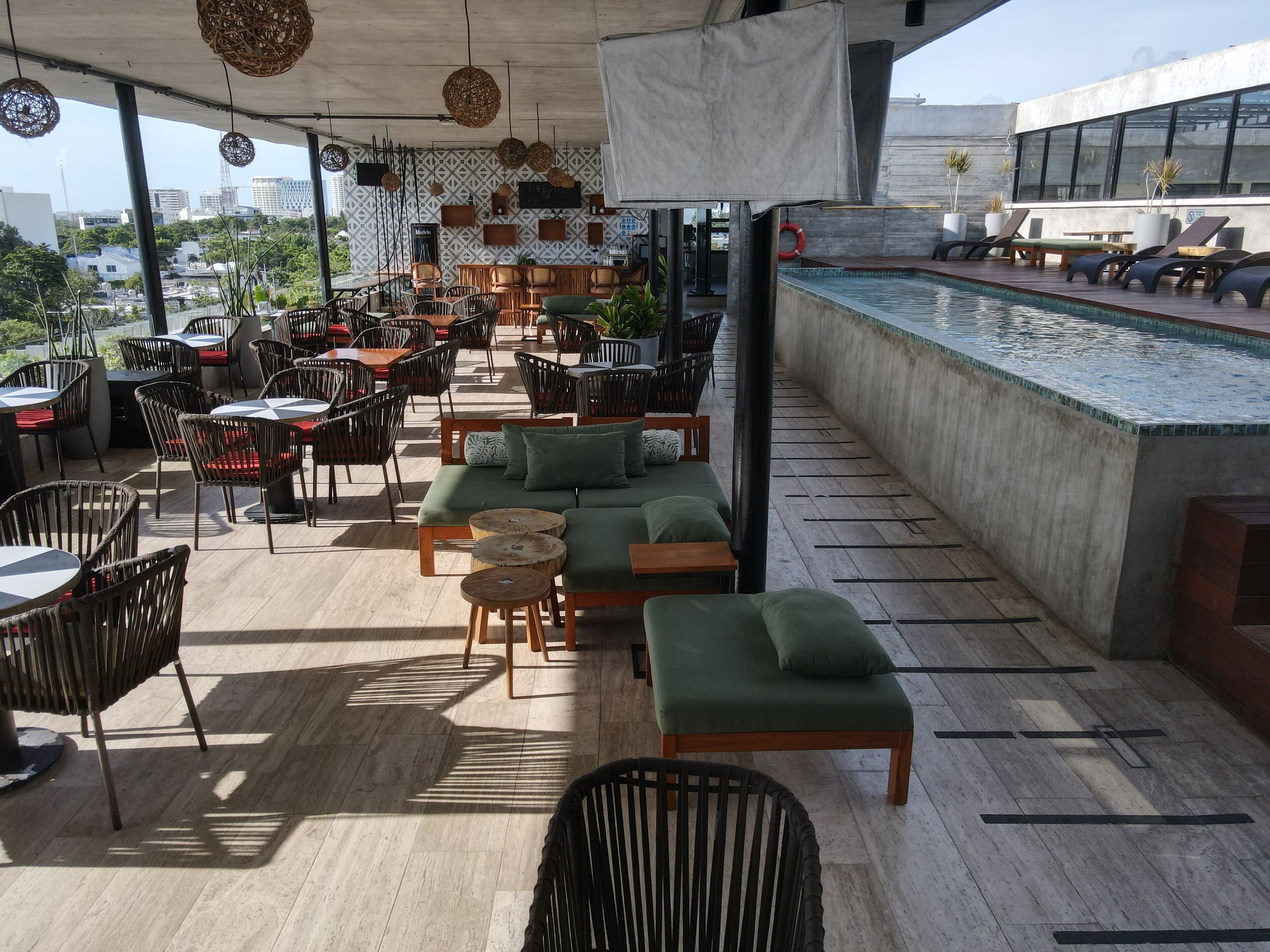 Un bar en la azotea con terraza, piscina y vistas a la ciudad.