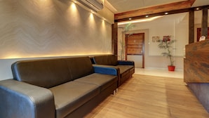 Un vestíbulo moderno con un sofá, piso de madera y una recepción.