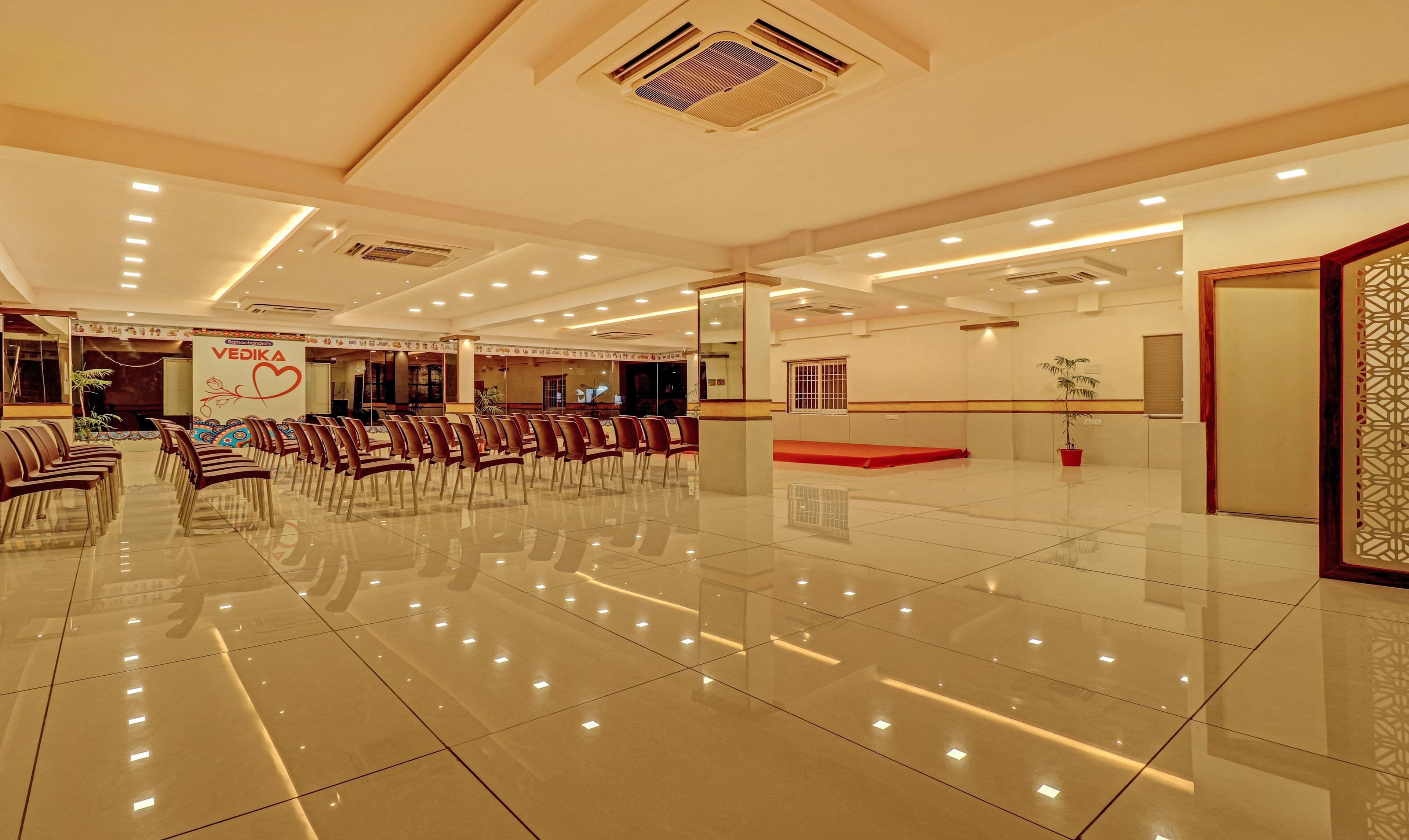 A spacious hall with rows of chairs, a reception desk, and a decorative wall with a heart design.