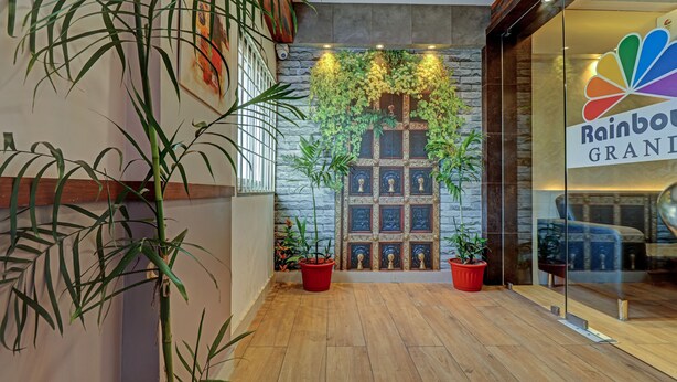 Un pasillo con suelo de madera, plantas en macetas y una pared con diseño de piedra y cuadros enmarcados.