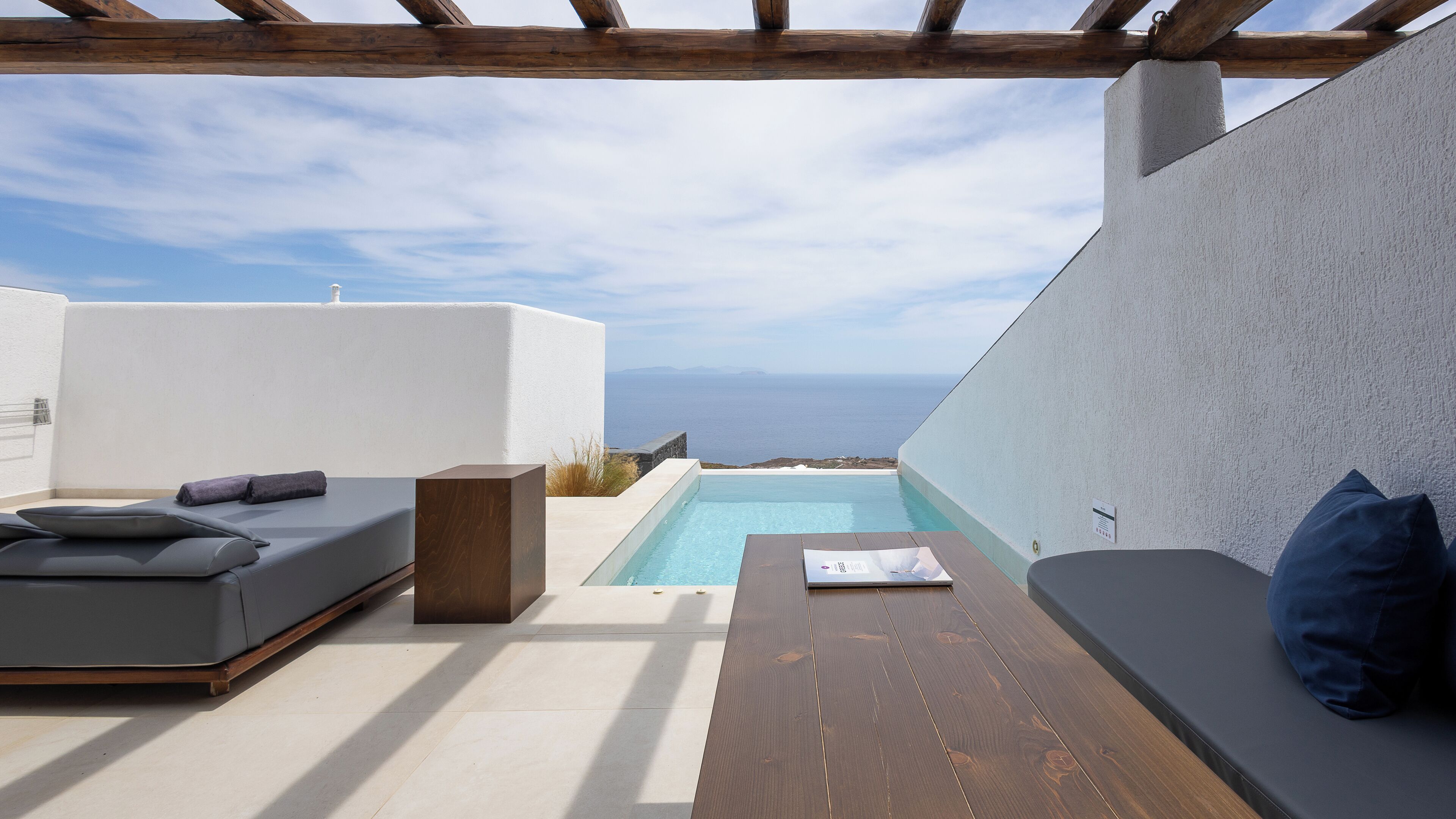 A rooftop terrace with a pool, seating area, and a view of the sea.