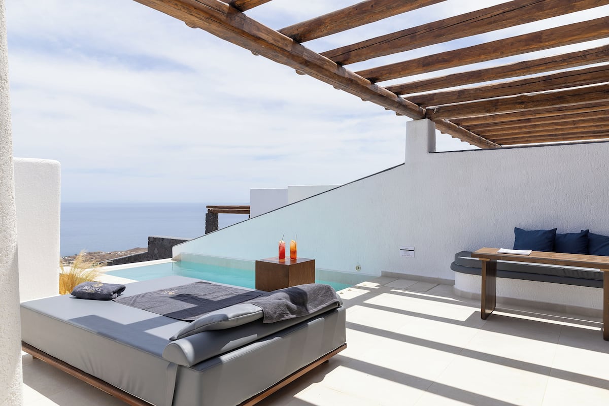 Un espace extérieur moderne, aménagé avec des sièges, une piscine, une pergola en bois et une vue sur la mer.