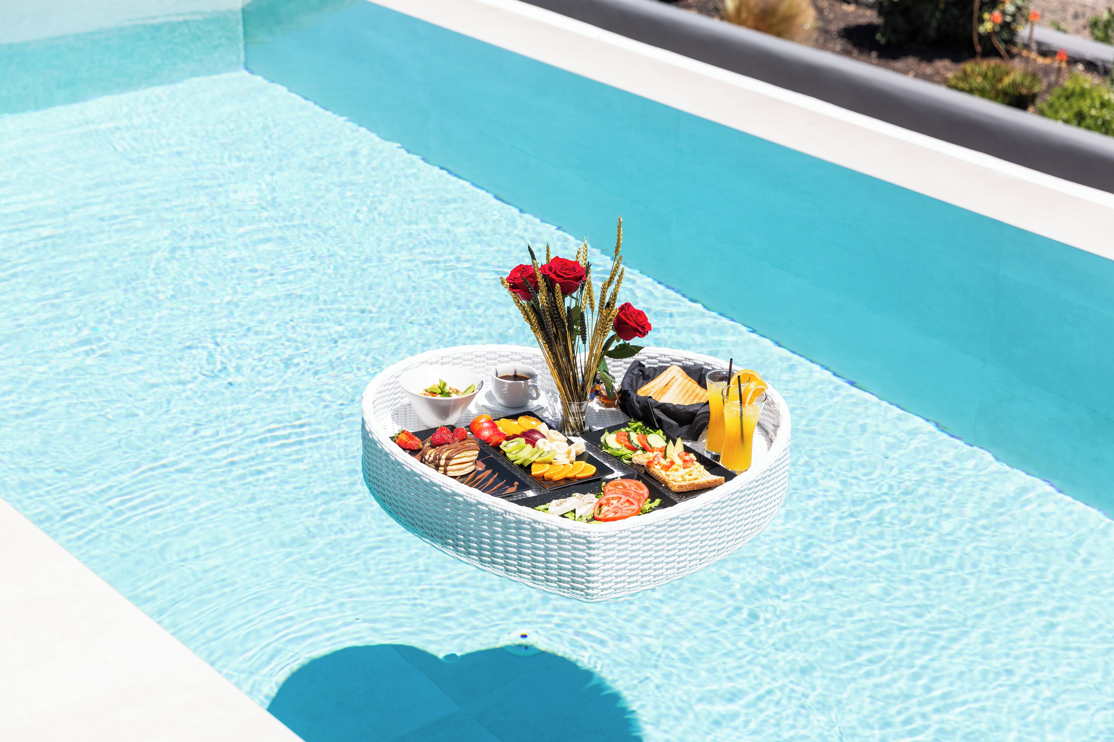A floating dining setup with food and drinks in a pool.