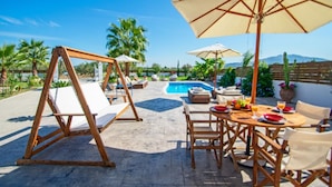 Eine Terrasse mit Schaukel, Sitzgelegenheiten und einem Pool.