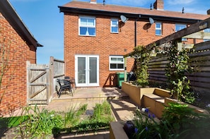 A brick house with a patio, a wooden gate, and a satellite dish. - A house that sleeps 4 guests  in 2 bedrooms (Cromer)