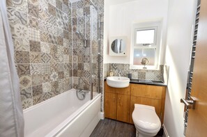 Un baño con baldosas estampadas, una bañera, un lavabo y un inodoro.