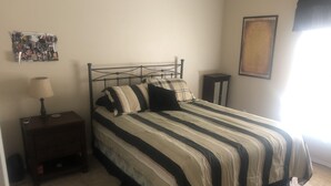 A bedroom with a metal bed frame, a bedside table with a lamp, and a framed picture on the wall. - Country house in Montrose (Montrose)