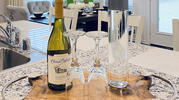 A dining area with a wooden table, a bottle of wine, and glasses.