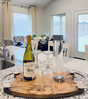 Een eethoek met een houten tafel, een fles wijn en glazen.