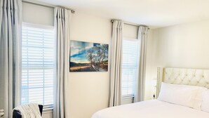 A bedroom with a large bed, a chair, and a painting on the wall.