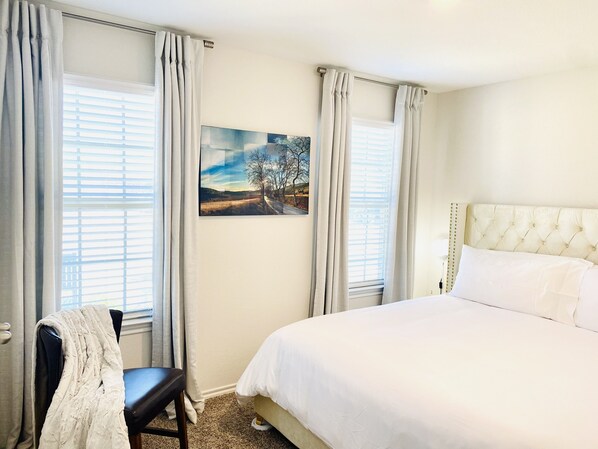 Een slaapkamer met een groot bed, een stoel en een schilderij aan de muur.