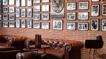A brick wall with framed black and white photographs, a leather couch, and a round table.