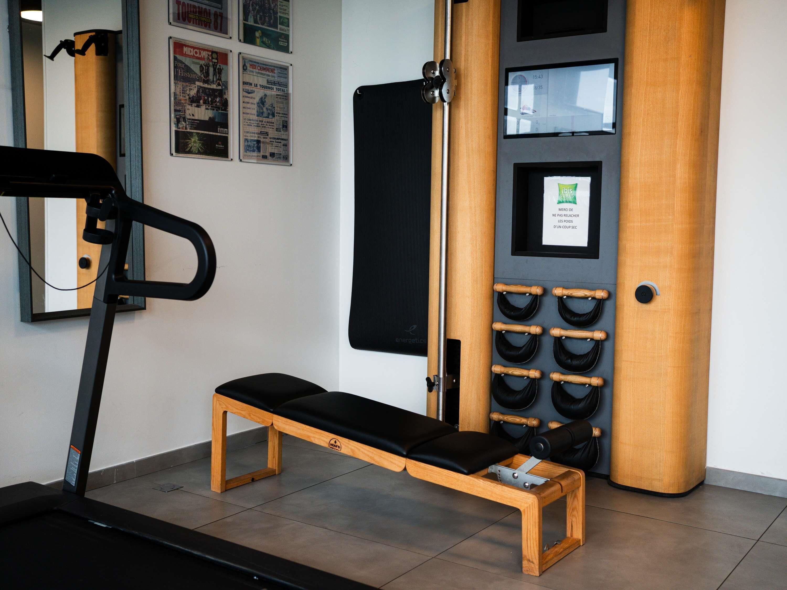A gym with a treadmill, a bench, and a wall-mounted exercise machine.