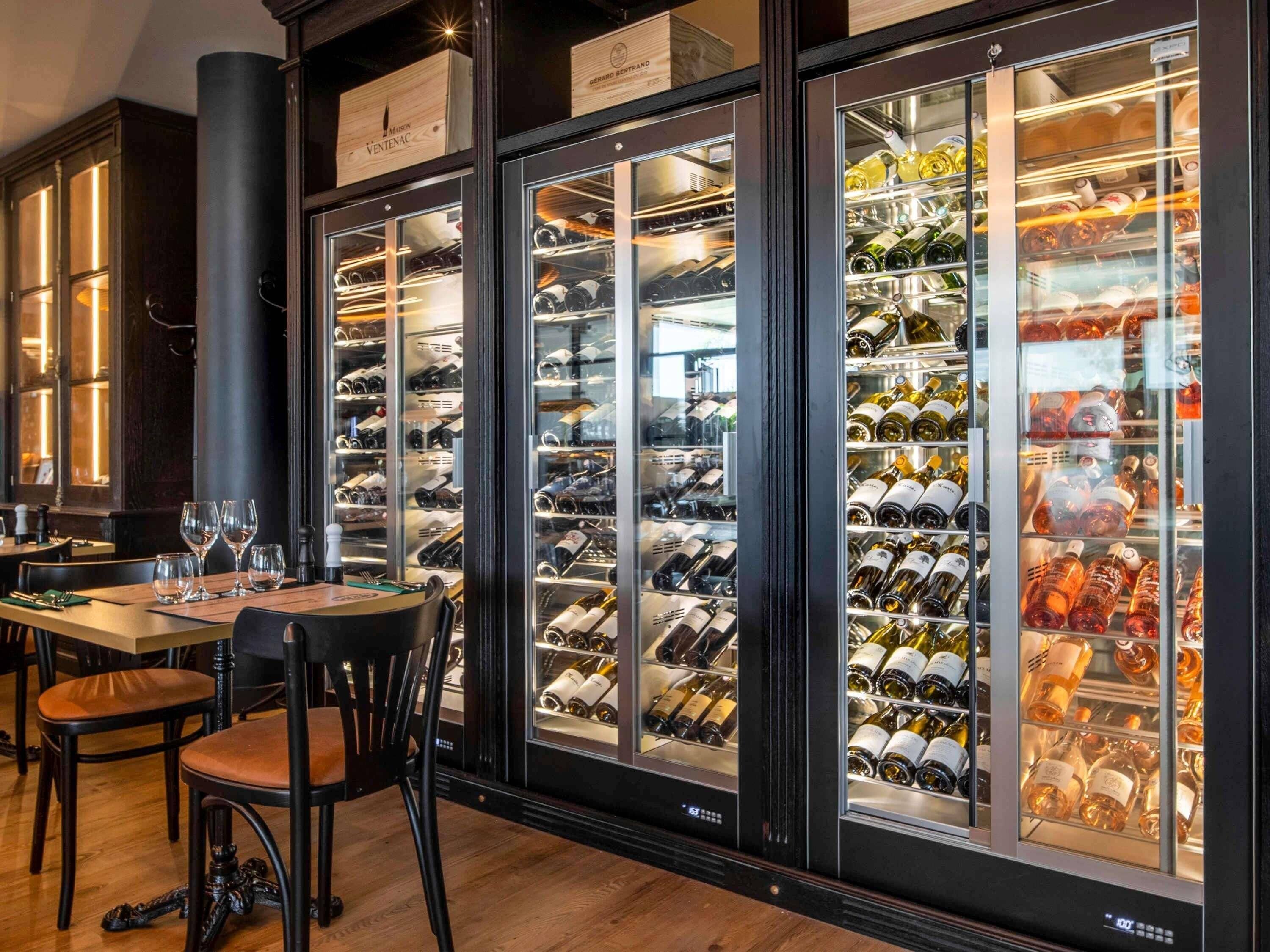 Une cave à vin dotée de plusieurs armoires à vitrines, remplies de bouteilles de vin.