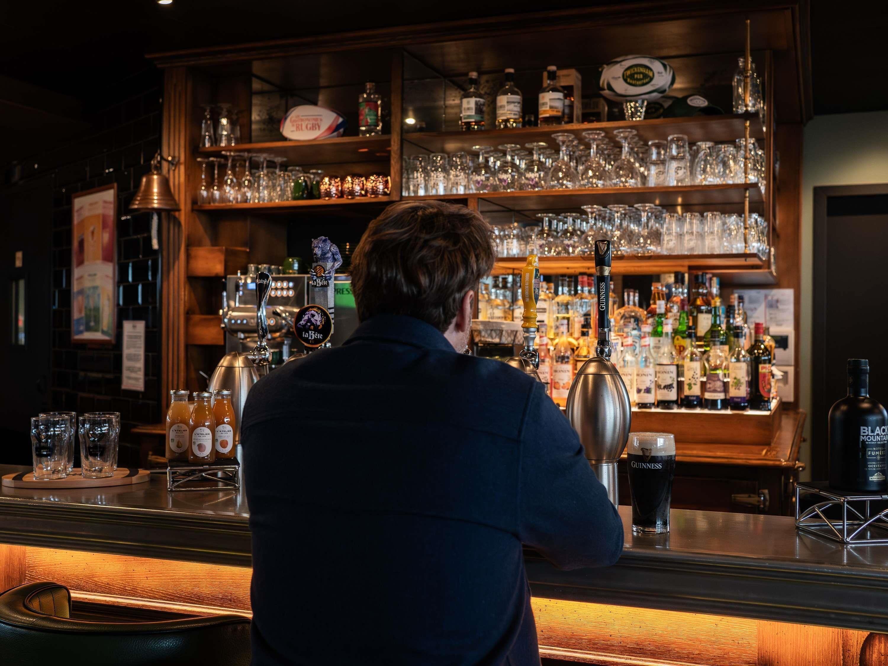 Un espace bar doté de plusieurs tireuses à bière, d’un assortiment de bouteilles et de verres.