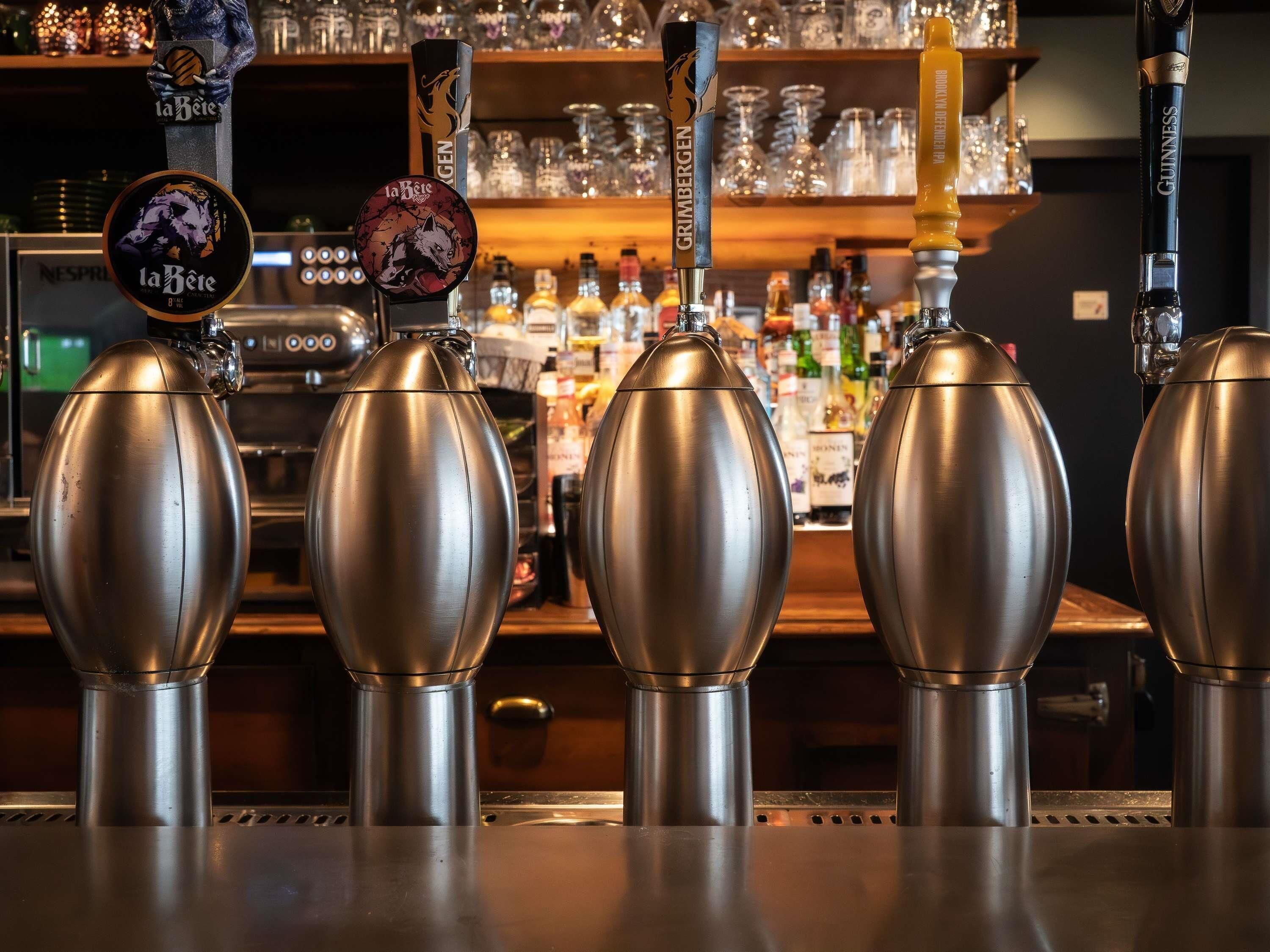 Un bar con múltiples grifos, incluyendo marcas como NESPIR, GRIMBERGEN y GUINNESS.
