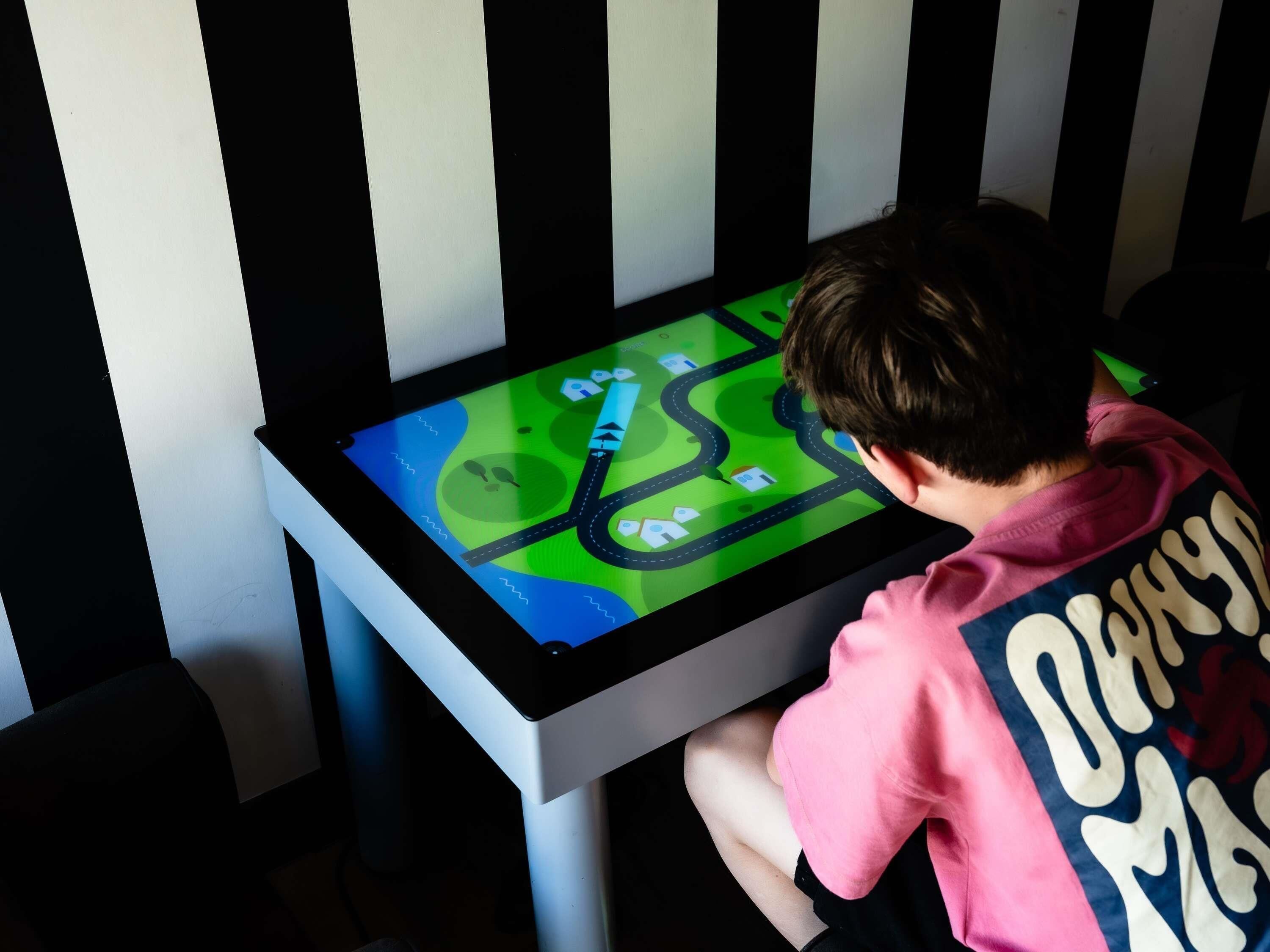 Un niño jugando a un juego en una mesa digital.