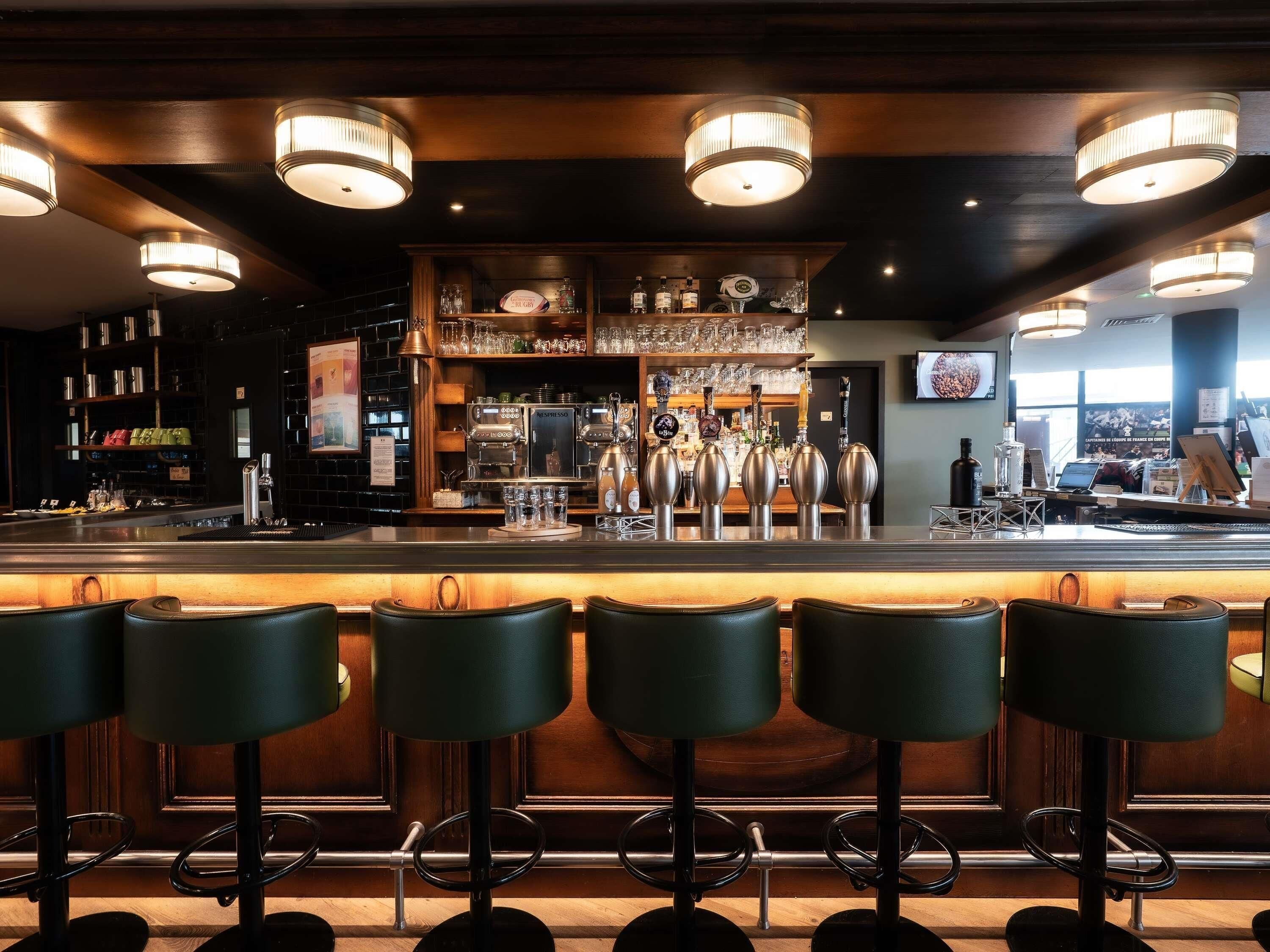 Een bar met verschillende krukken, een bar en een koffieapparaat.