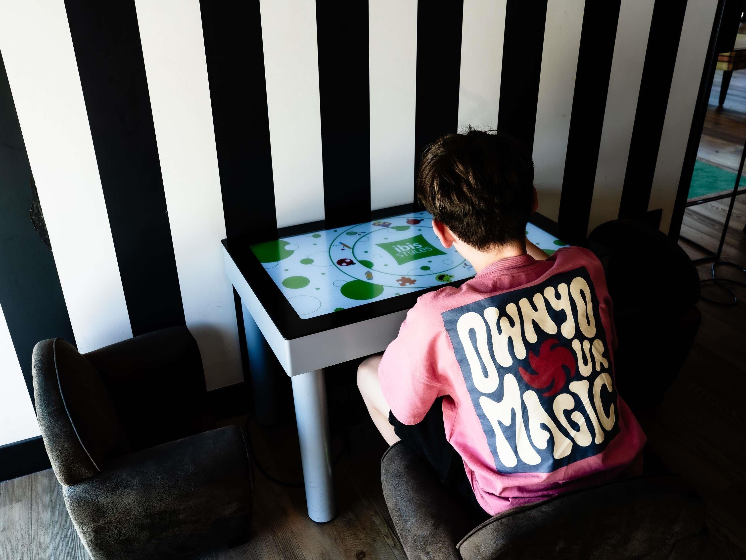 A child playing a game on a table with a striped wall in the background.