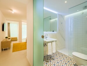 Ein modernes Badezimmer mit Glasabtrennung, Waschbecken, Spiegel, Dusche und Toilette.
