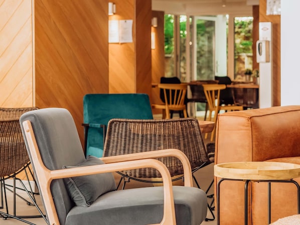 L’intérieur d’un café moderne, avec des chaises en osier, un fauteuil bleu rembourré et une table en bois.