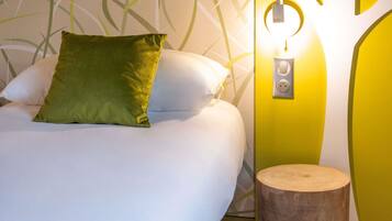 A bed with pillows, a bedside table, and a wall-mounted light fixture.