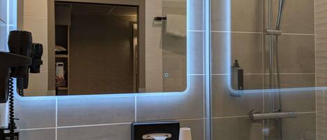Un baño moderno con un espejo grande, un lavamanos, una toalla y una cabina de ducha de vidrio.