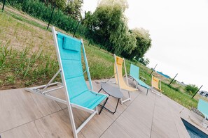 Des fauteuils de jardin confortables sur une terrasse avec piscine.