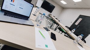 A conference room with a laptop displaying a spreadsheet, water bottles, a smartphone, and a notepad on the table. - ibis Styles Contres Cheverny (Le Controis en Sologne)