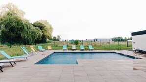 A swimming pool with lounge chairs and a tiled deck. - ibis Styles Contres Cheverny (Le Controis en Sologne)