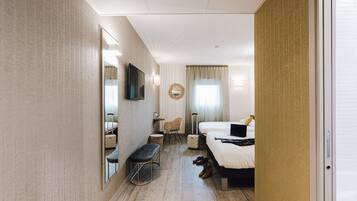 Ett hotellrum med en stor säng, ett skrivbord, en stol, en tv och en spegel.