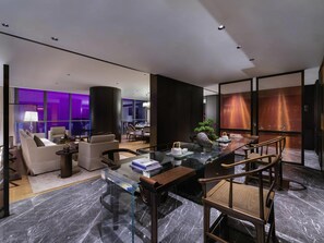 A modern interior with a glass coffee table, leather sofas, a dining area, and a large window with purple lighting. - Novotel Xian Xixian (Xi'an)