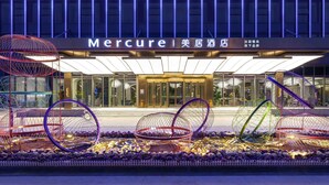 Das moderne Hotel von außen, mit einem markanten Eingangsbereich und dekorativen Sitzgelegenheiten.