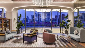 Eine moderne Lounge mit Blick auf die Stadt, ausgestattet mit einem Kronleuchter, bequemen Sitzgelegenheiten und großen Fenstern.