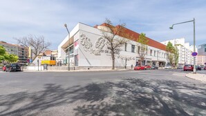 A building with a large mural on the facade, a street with cars, and a clear sky. - GuestReady - Tower- 3 Bedroom Apt in Saldanha (Lisboa)
