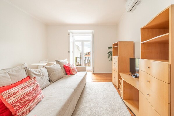 A living room with a sofa, a TV, and wooden shelving.