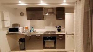 A compact kitchen with a microwave, stove, oven, and a sink. - Maison au Calme à Proximité des Plages (Querrien)