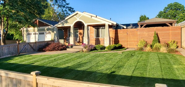 A residential house with a well-maintained lawn, a garage, and a wooden fence.