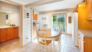 A kitchen with wooden cabinets, a dining table with chairs, a built-in oven, and a view of the outdoors through a sliding door. - 3 bed 3 bath, Well maintained, Outside heated pool (Cedar)