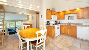 A kitchen with wooden cabinets, a white stove, and a dining area with a wooden table and white chairs. - 3 bed 3 bath, Well maintained, Outside heated pool (Cedar)