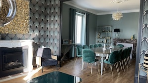Un coin repas avec une table en marbre, des chaises vertes et une cheminée.