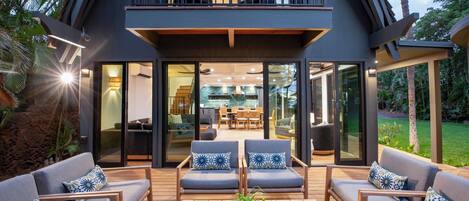 A modern house with a balcony, outdoor seating, and a view of the interior.