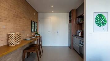 A modern kitchen with a brick wall, wooden countertop, and a dining area with chairs.
