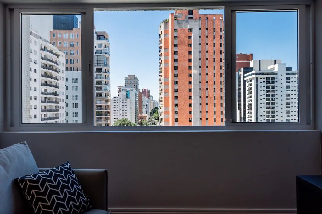 A room with a large window overlooking a cityscape with various buildings.