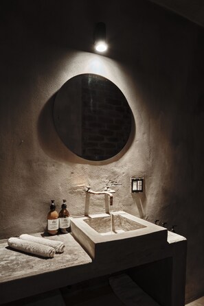 Ein Badezimmer mit einem runden Spiegel, einem Waschbecken und zwei Lotionflaschen.