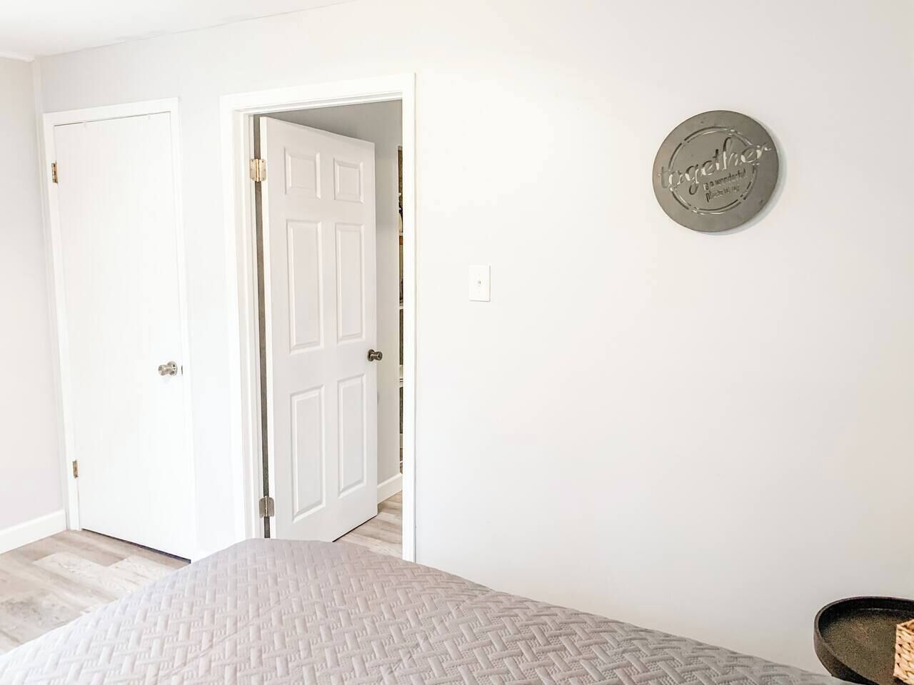 A bedroom with a bed, a door, and a wall-mounted sign.