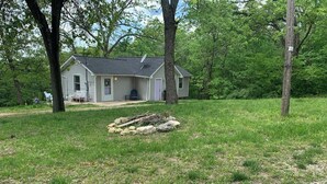 A house with a porch, surrounded by a grassy yard and trees.