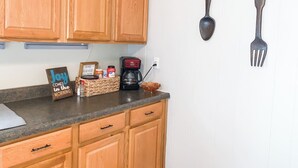 A kitchen with wooden cabinets, a coffee maker, a basket of bread, and a sign that says "Jay comes in the morning."