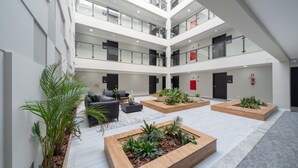 A spacious atrium with multiple levels, wooden planters with plants, and a seating area with sofas and a coffee table. - Laghetto Stilo Vita (Gramado)